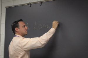 Mr. Catapano writes the name of the new English book on the board.